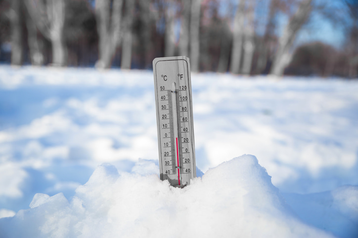 A thermometer showing freezing temperatures outside in a pile of snow